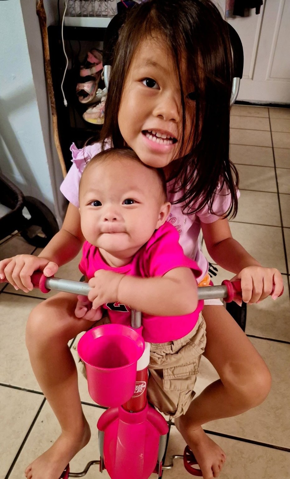 Suryla holding baby Koa during a playful sibling moment